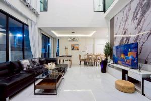 un salon avec un canapé noir et une table dans l'établissement Walters House Pool Villa Pattaya, à Ban Huai Yai