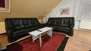 Una sala de estar con un sofá de cuero negro y una mesa de café. en FeWo Langewerth, en Wilhelmshaven