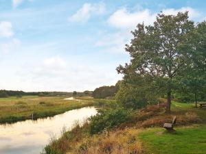 a bench sitting next to a river with a tree at 6 person holiday home in Ans By in Roe +17 photos