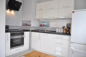 una cocina blanca con armarios y electrodomésticos blancos en Apartamenty Tespis - Andersa, en Katowice