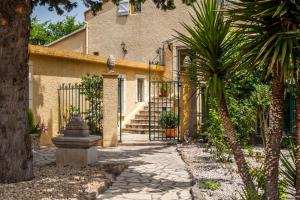 uma casa com um portão e palmeiras em frente em Domaine De Bailheron em Béziers