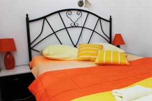 1 dormitorio con 1 cama con almohada naranja y amarilla en B&B Laguna, en Ðakovo