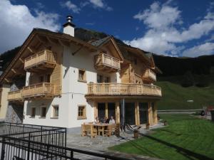 a house with people sitting at a table in front of it at B&B Ecohotel Chalet des Alpes in Livigno