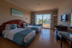 a hotel room with two beds and a television at JAZ Royal Palmariva in Hurghada +24 photos