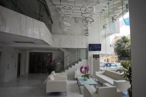 un vestíbulo con sofás blancos, mesas y flores en Naki Suites @ Silvertown, en Phnom Penh