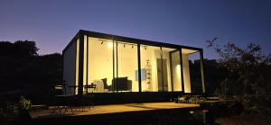 een glazen huis met een tafel en stoelen op een terras bij Goshen in ‘Isfiyā