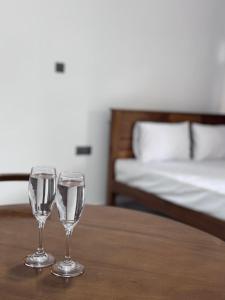 two wine glasses sitting on a table in a bedroom at Hirudee Villa in Unawatuna
