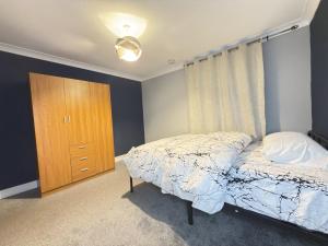 a bedroom with a bed and a wooden cabinet at Bright Double Room in Wellingborough in Harrowden