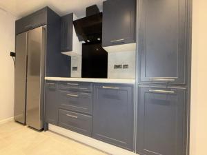 a kitchen with gray cabinets and a refrigerator at Bright Double Room in Wellingborough in Harrowden