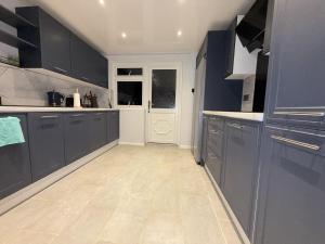 a kitchen with blue cabinets and a white floor at Bright Double Room in Wellingborough in Harrowden +11 photos