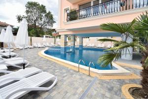 a hotel swimming pool with lounge chairs and umbrellas at Sirena Palace Family Hotel in Obzor
