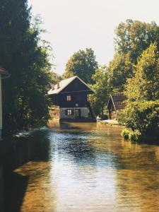 a house sitting on a river next to a house at Room Bea Rastoke in Slunj