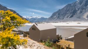 a house on the side of a river with mountains at Khoj Resorts Shigar in Shigar