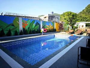 a swimming pool with a person standing next to a mural at Hana Homestay KGR in Xuan Dam