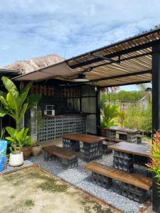 a patio with wooden tables and benches under a pergola at Lantamangrove in Ko Lanta