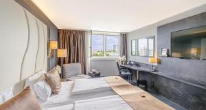 a hotel room with a large bed and a desk at PLAZA Premium Darmstadt in Darmstadt +73 photos