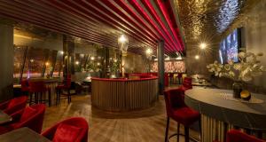 a restaurant with red chairs and a bar at PLAZA Premium Darmstadt in Darmstadt