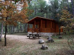 a wooden cabin in the woods with a picnic table at Cabañas Llano de los Conejos in Cañamares