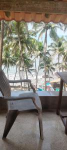 a chair sitting in front of a window looking at the beach at Ludu guest house in Arambol
