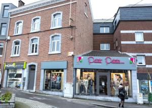 una mujer caminando por una calle frente a una tienda en Le Coin Cocoon Bis en Aywaille