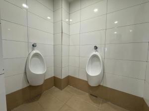 two urinals in a bathroom with white tiled walls at Swing & Pillows - CIQ Johor Bahru in Johor Bahru +19 photos