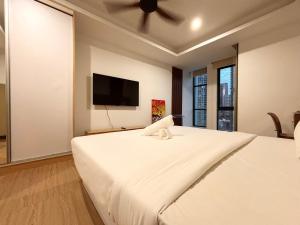 a bedroom with a large white bed and a flat screen tv at Casa Residency Bukit Bintang by PILLOWTALKS in Kuala Lumpur