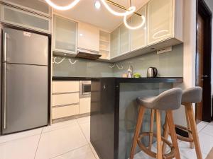 a kitchen with a stainless steel refrigerator and a stool at Casa Residency Bukit Bintang by PILLOWTALKS in Kuala Lumpur