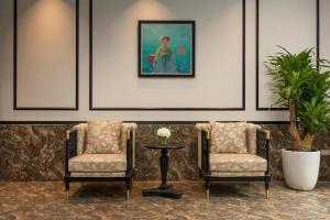two chairs and a table in a room with a painting at Grand Vĩnh Tuy Hanoi Hotel&Spa in Mai Phúc