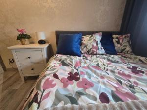 un letto con piumone floreale e comodino di Apartament Ami a Płock