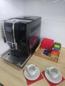 una macchina per il caffè su un tavolo con due tazze e piatti di Apartament Ami a Płock