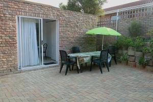 a patio with a table and chairs and an umbrella at Weltevrede guest unit in Mossel Bay