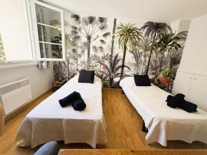 2 camas en una habitación con palmeras en la pared en Bastide Terrieu - domaine avec piscine et terrain de boules, climatisation, en Saint-Mathieu-de-Tréviers 75 fotos más