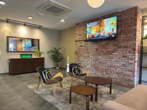 a living room with a tv on a brick wall at Swing & Pillows - CIQ Johor Bahru in Johor Bahru