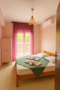a bedroom with a bed and a window with pink curtains at Epanomi Apartments in Epanomi