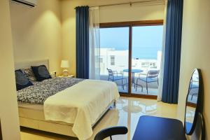 a bedroom with a bed and a balcony with chairs at Wateera Jebel Sifah in As Sīfah +272 photos