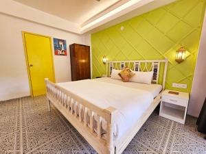 een slaapkamer met een groot bed met een gele muur bij Spacious Condo with Pool View in Anjuna +9 foto's