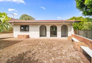 ein kleines weißes Haus mit einem Zaun davor in der Unterkunft Spacious 3-Bedroom Retreat Near Airport & City in Auckland