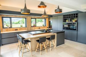 a kitchen with a large island with bar stools at La Maison Bas Lachamp - Luxuary Mountain Villa in Bellefosse