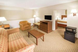 a hotel room with a couch and a bed at Baymont by Wyndham Mobile/ I-65 in Country Club Estates