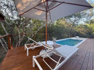 a deck with an umbrella and chairs and a pool at The Dome Luxury Safari Villa in Hluhluwe +28 photos