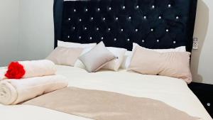 a large bed with white pillows and a black headboard at The Perazim Place in Hazyview