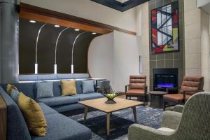 ローリーにあるHyatt Place Raleigh Caryのソファ、テーブル、暖炉が備わるロビー