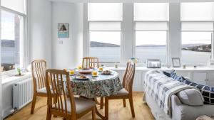 a dining room with a table and chairs with a view of the water at The Hidden Asset- Rothesay, Isle of Bute in Rothesay +6 photos