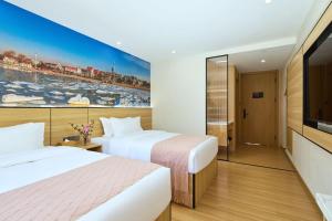 a hotel room with two beds and a flat screen tv at Floral Hotel Beidaihe Migao Intelligent Hotel in Qinhuangdao +18 photos