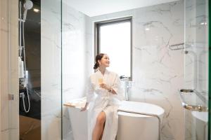 a woman sitting on a toilet in a bathroom at Radisson Hotel Chateau de Bangkok in Bangkok
