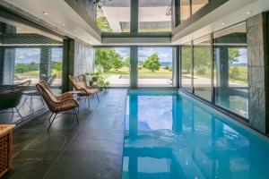 a swimming pool in a house with glass windows at La Maison Bas Lachamp - Luxuary Mountain Villa in Bellefosse