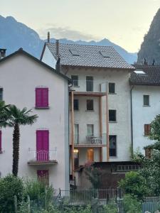 a white building with purple doors and a palm tree at Historische Unterkunft Casa Tre Valli in Biasca