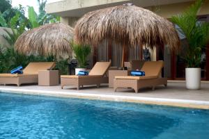 a group of lounge chairs next to a swimming pool at Gilded Palms Villa, Ubud Payangan, Bali in Payangan