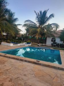 a swimming pool in front of a house with palm trees at Elegant Double Big Room at Villa Paradise in Diani Beach