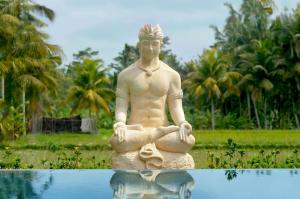 a statue of a man sitting in the water at Gilded Palms Villa, Ubud Payangan, Bali in Payangan